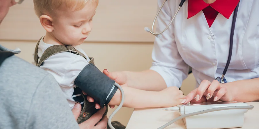 Pressão alta em criança: medida da pressão na consulta de cardiopediatria Medida da pressão arterial no braço de uma criança para identificar pressão alta em criança