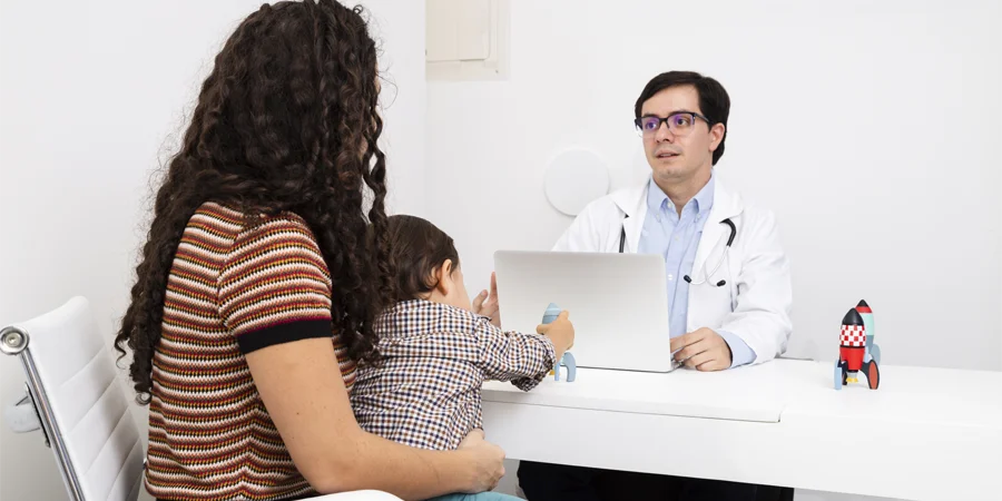 Histórico familiar de doença cardíaca: avaliação da criança com o cardiopediatra Cardiopediatra conversando com a família sobre histórico familiar de doença cardíaca durante a consulta da criança